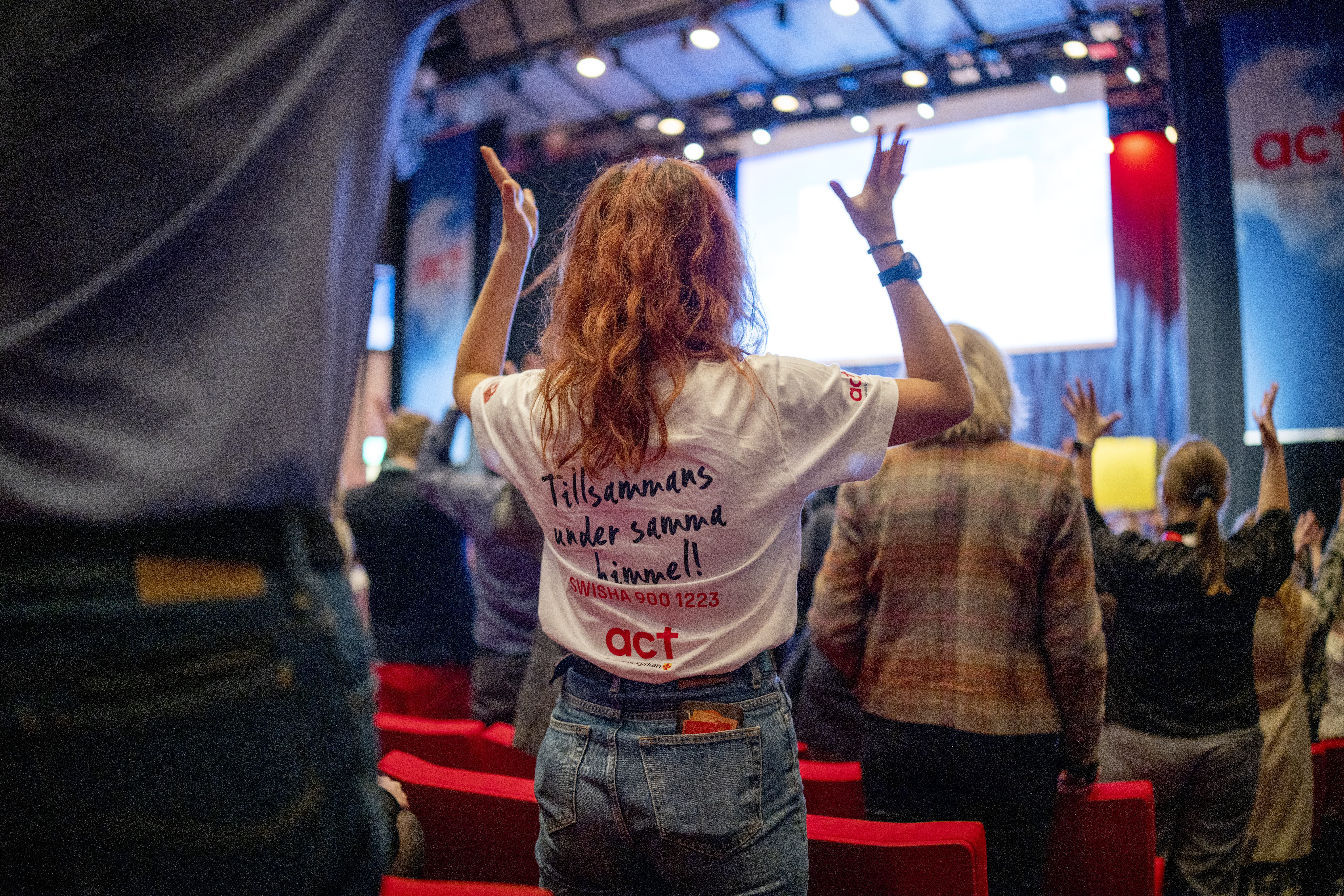Engagerad ung kvinna håller upp armarna i luften i ett folkhav