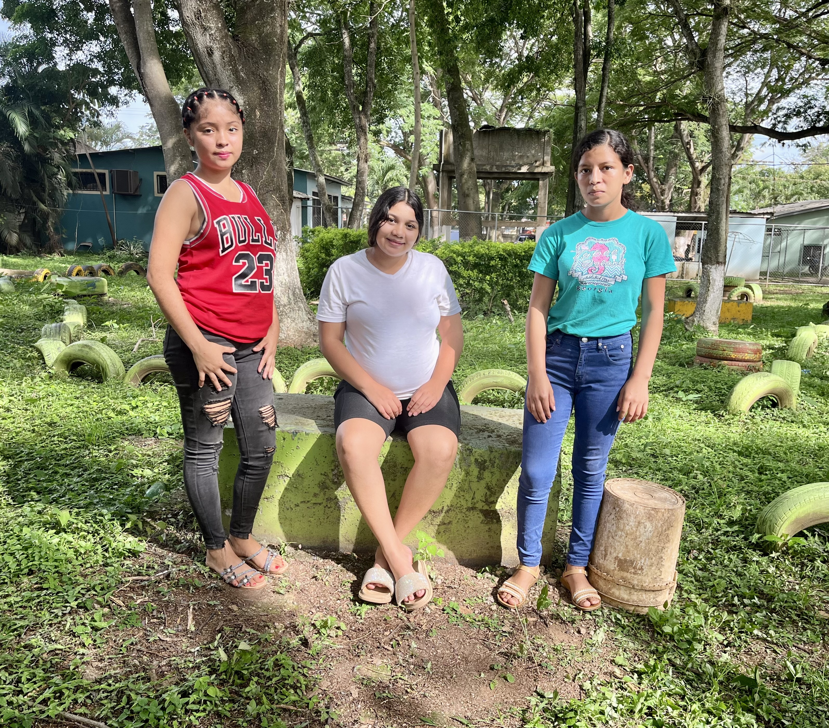 Tre tonårsflickor tittar mot kameran. 