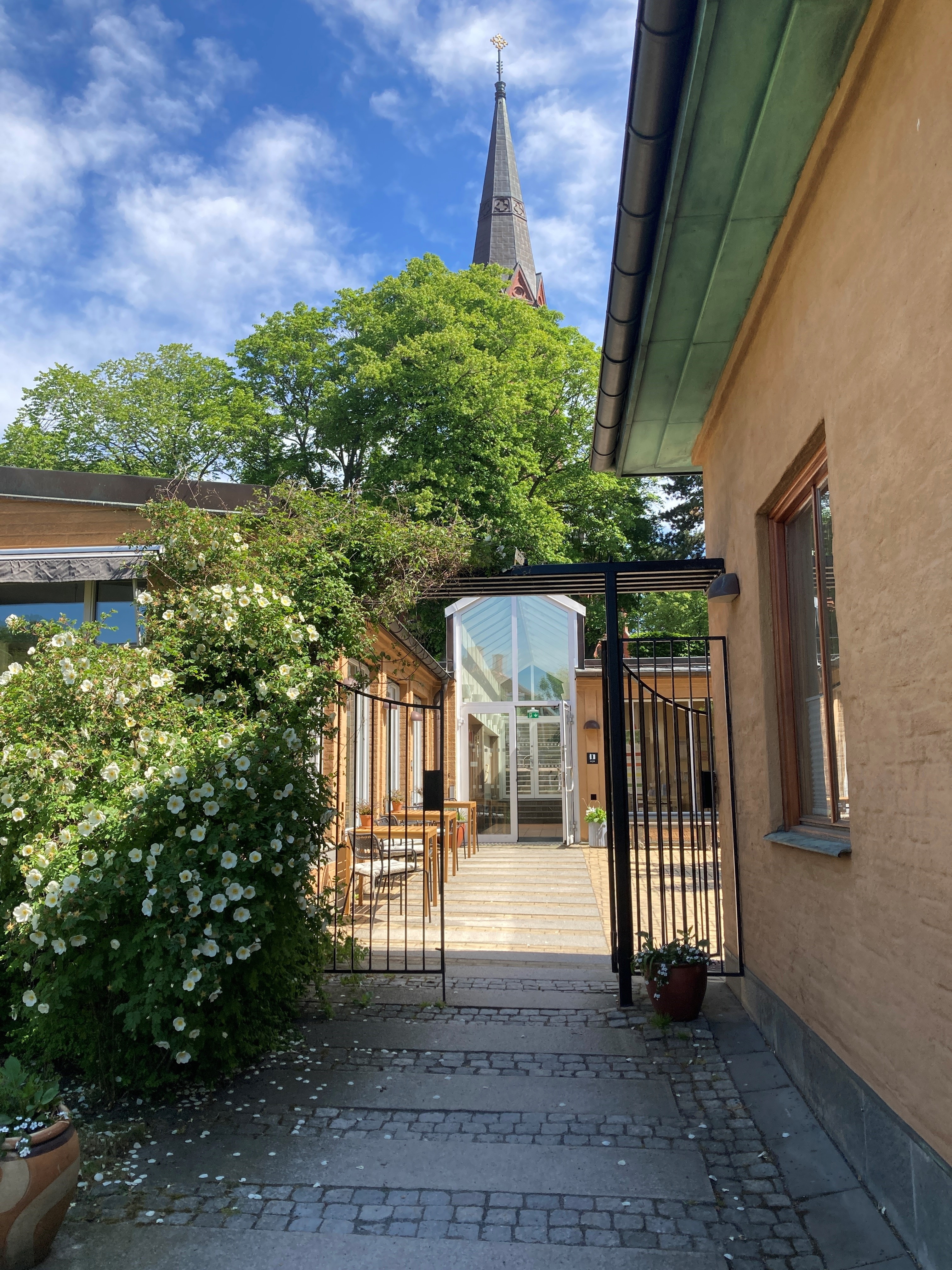 Terrakottafärgad byggnad med entré med gallergrind mot en innergård.