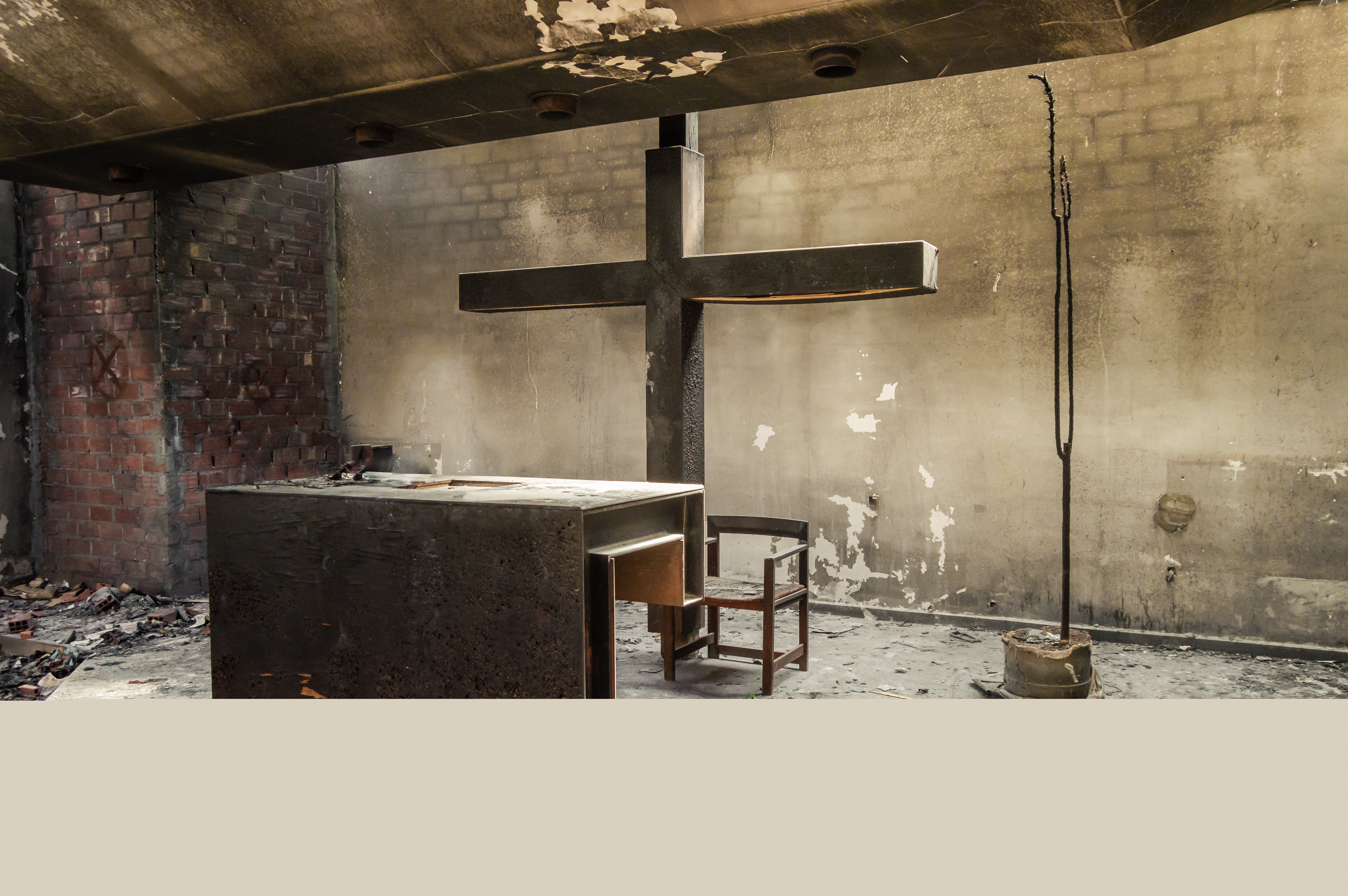 Svartbränt sotigt altare och stort krucifix s inne i ett kyrkorum, förstört av eldsvåda.