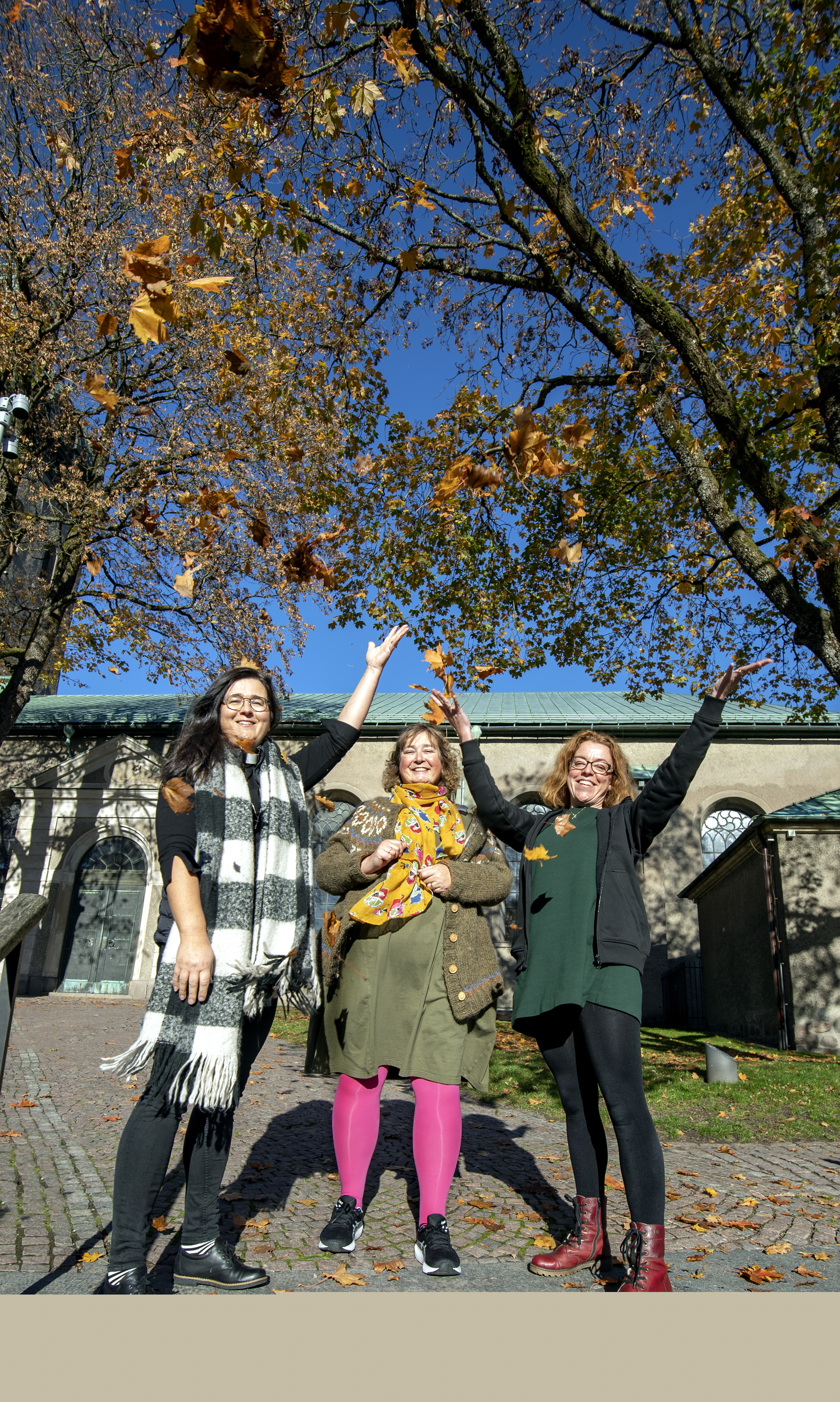 Tre kvinnor på trappa utanför kyrka. Höstlöv och blå himmel.