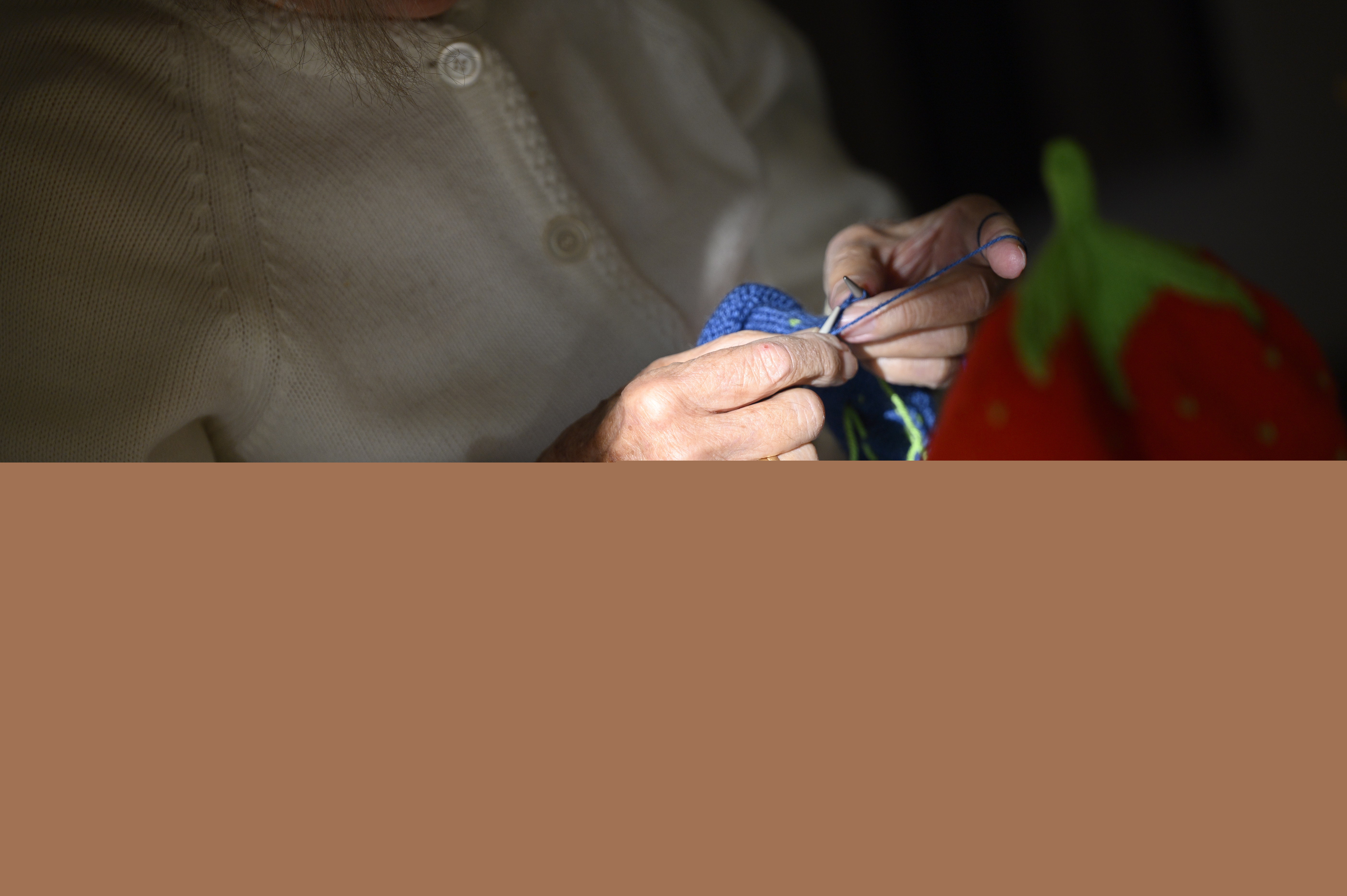 En äldre dam sitter och stickar.