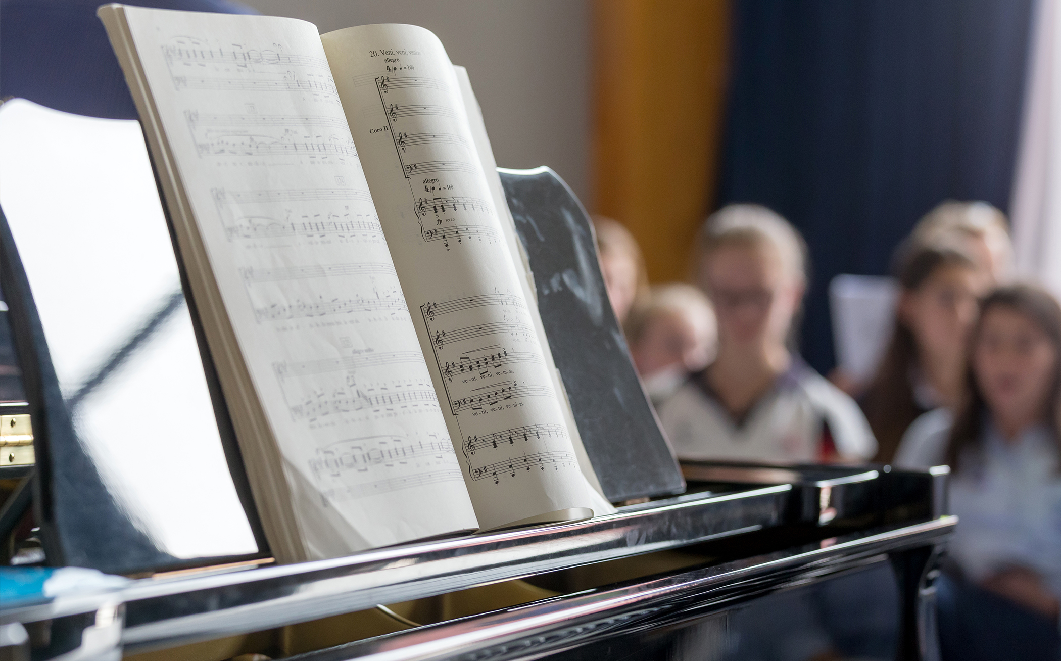 En orgel/ett piano och ett nothäfte, några människor i bakgrunden. 